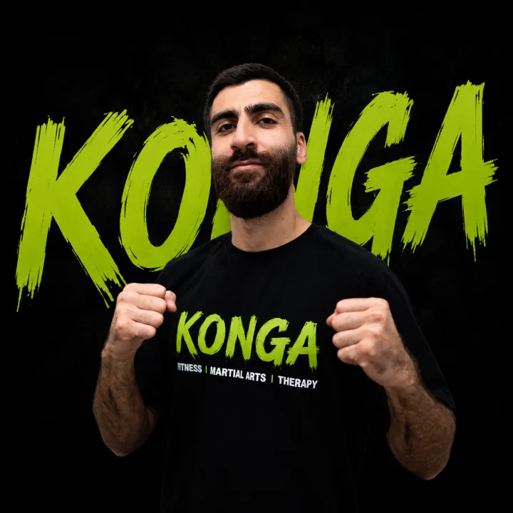 Coach Eyad holding a boxing stance in front of the Konga logo