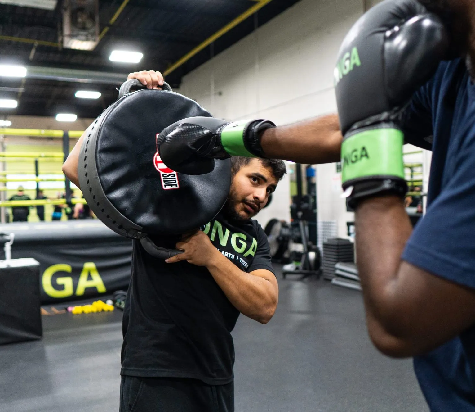 Coach Javier holding focus mitts for a boxing student
