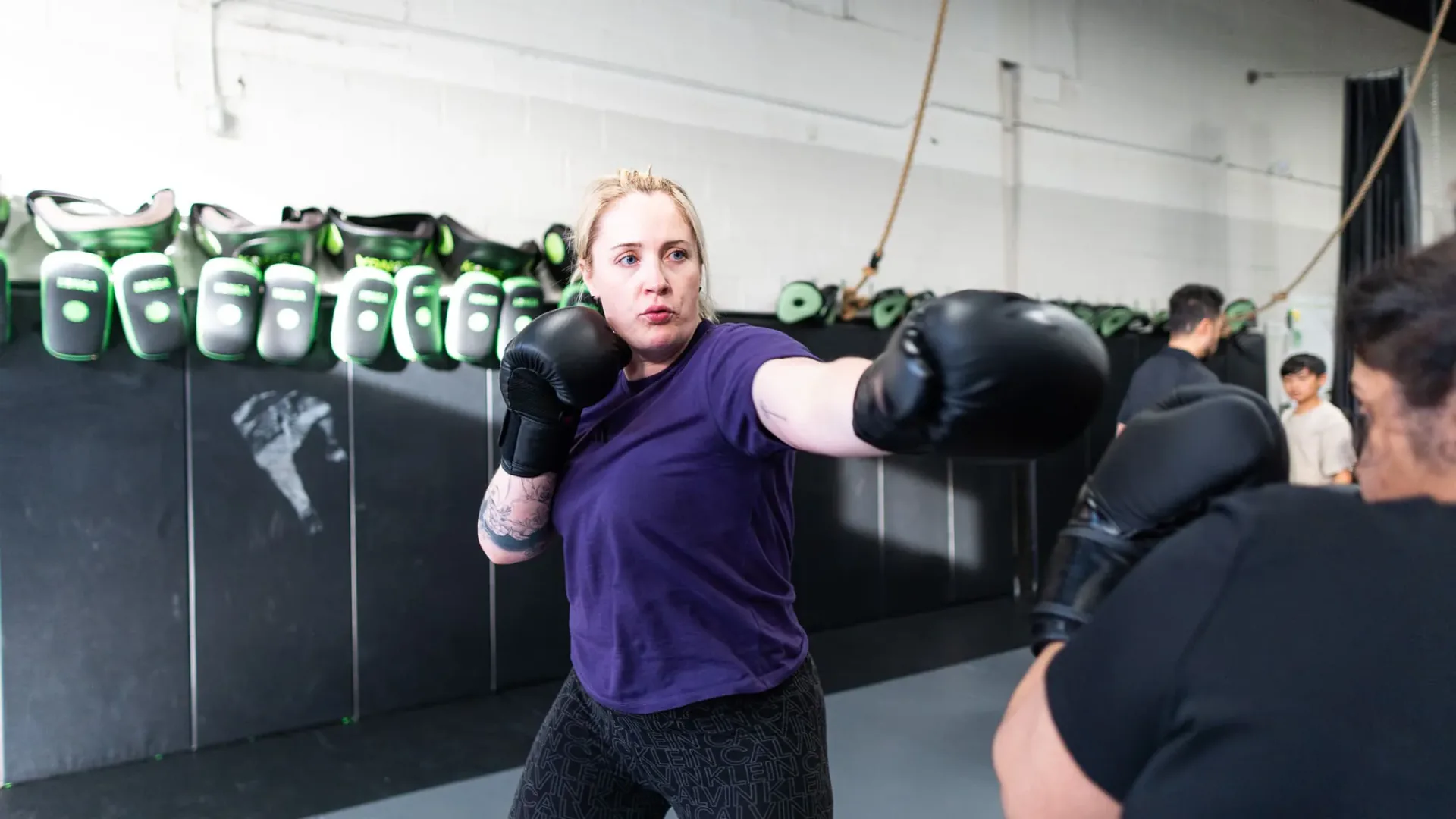 Woman practising a punch with black boxing gloves