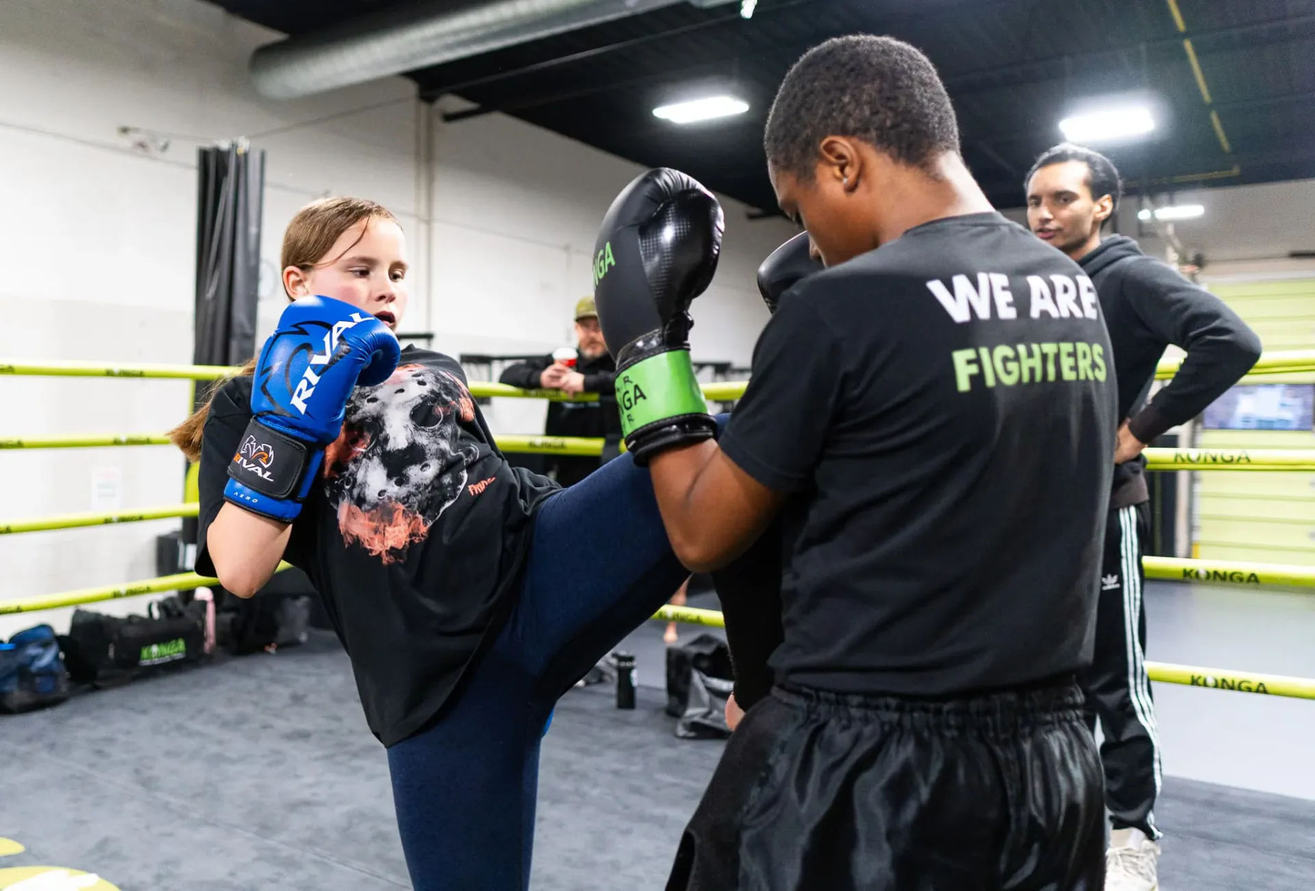 Child practising a kick against pads held by a coach