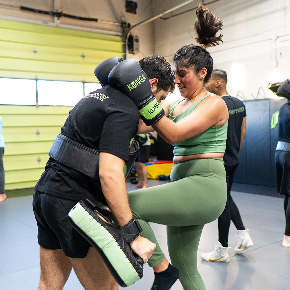 Woman practising a knee strike during Muay Thai training