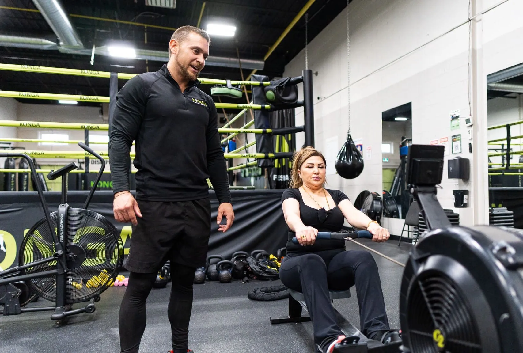 Trainer supervising a member on a rowing machine