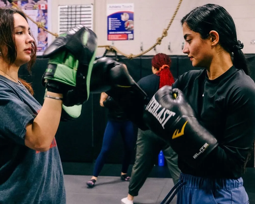 Two women practising boxing with focus mitts