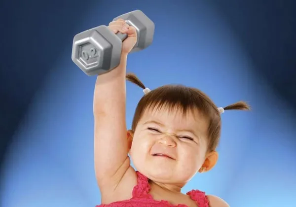 Young child lifting a small dumbbell overhead