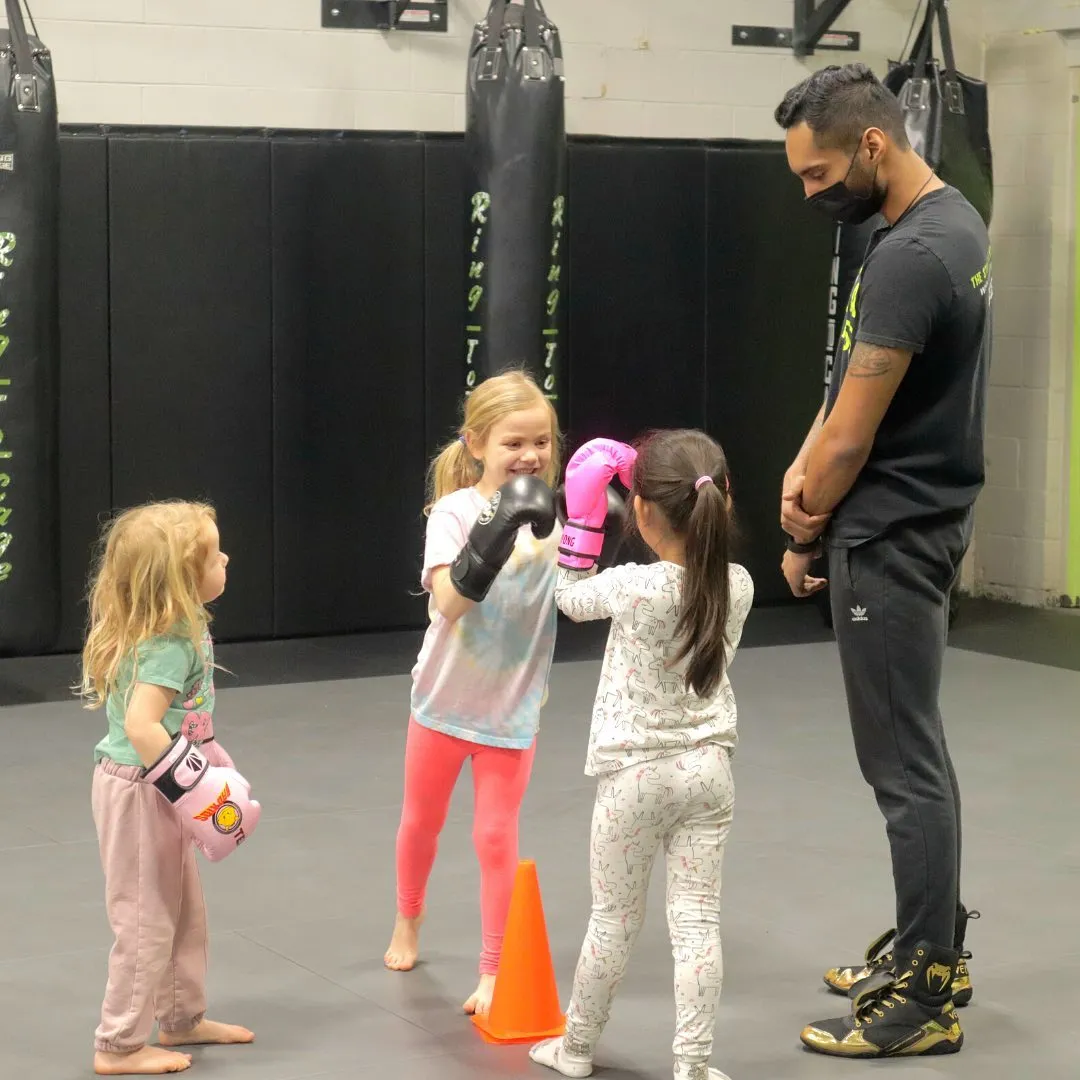Coach guiding young children through a boxing activity