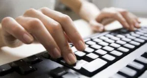 Hands typing on a computer keyboard