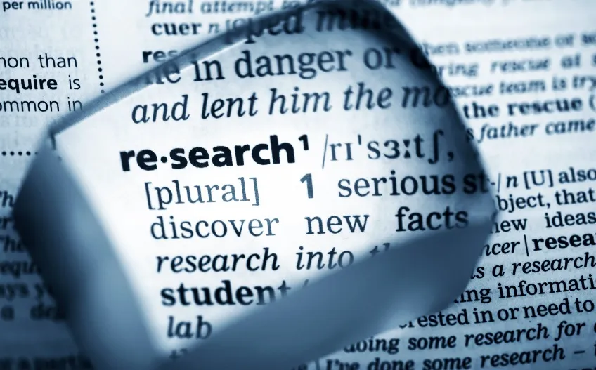Magnifying glass enlarging the dictionary definition of research