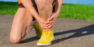 Runner kneeling and holding the front of the lower leg