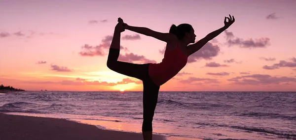 Silhouette of a person holding a standing yoga balance on a beach