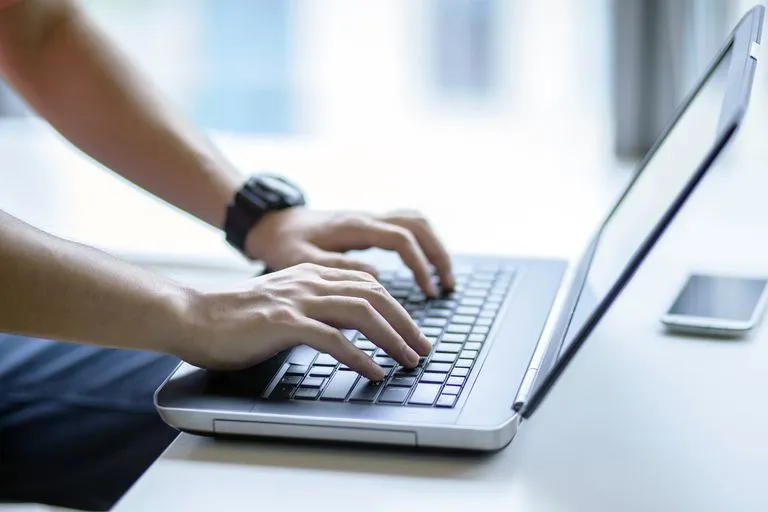 Hands typing on a laptop