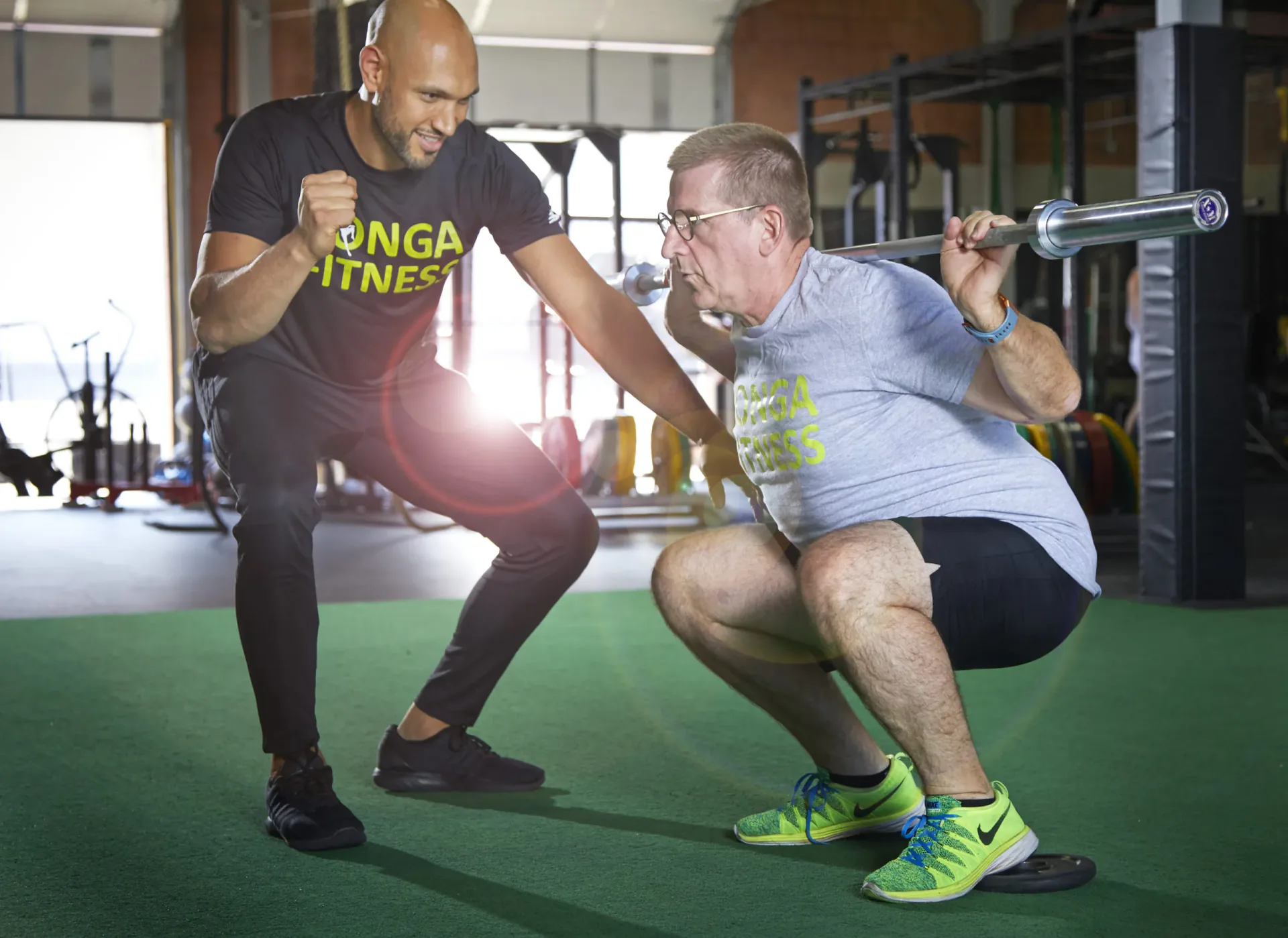 Two trainers demonstrating a squat at Konga Fitness