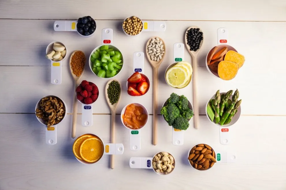 Small bowls and spoons containing portions of fruit, vegetables and other foods