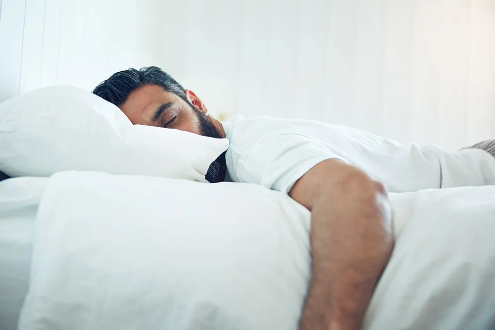 Person sleeping under white bedding
