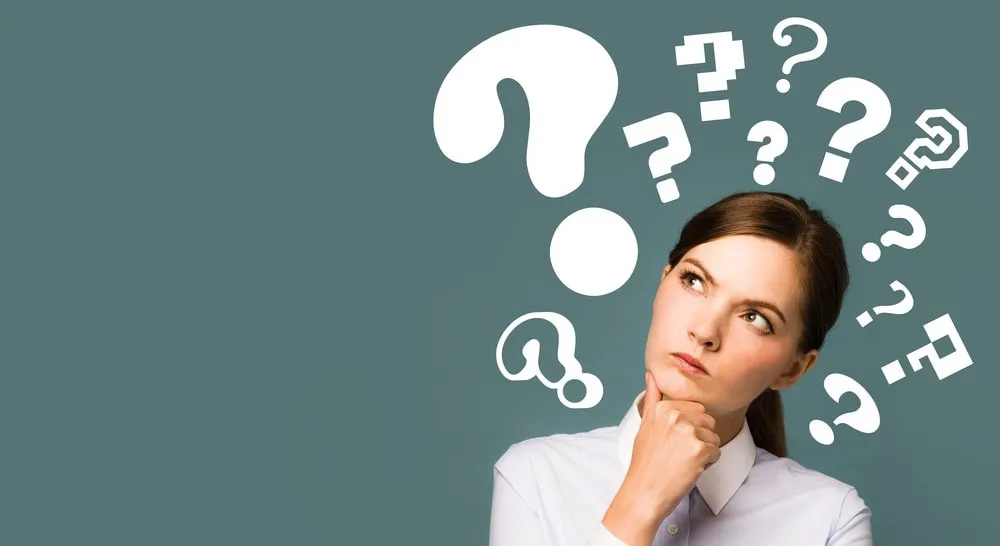 Woman looking thoughtful beneath illustrated question marks