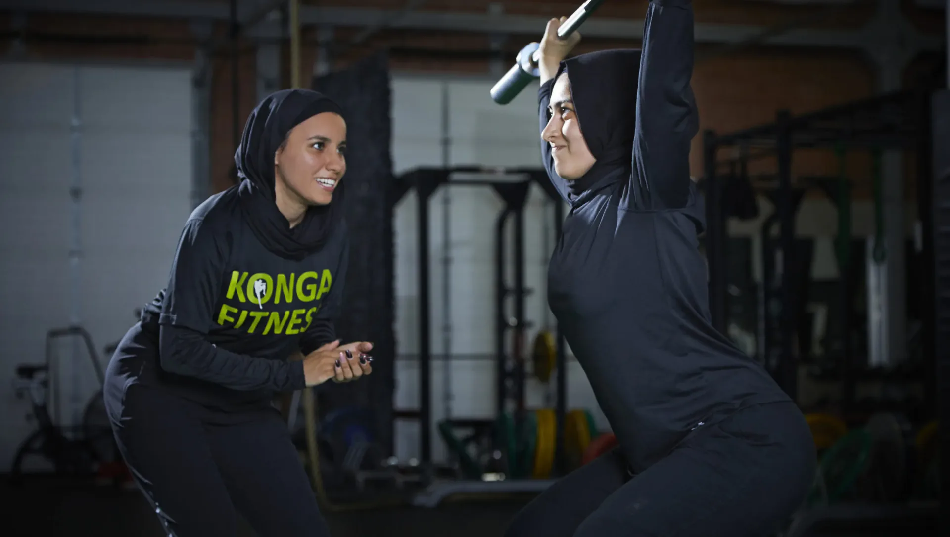 Trainer coaching a member through an overhead dumbbell exercise