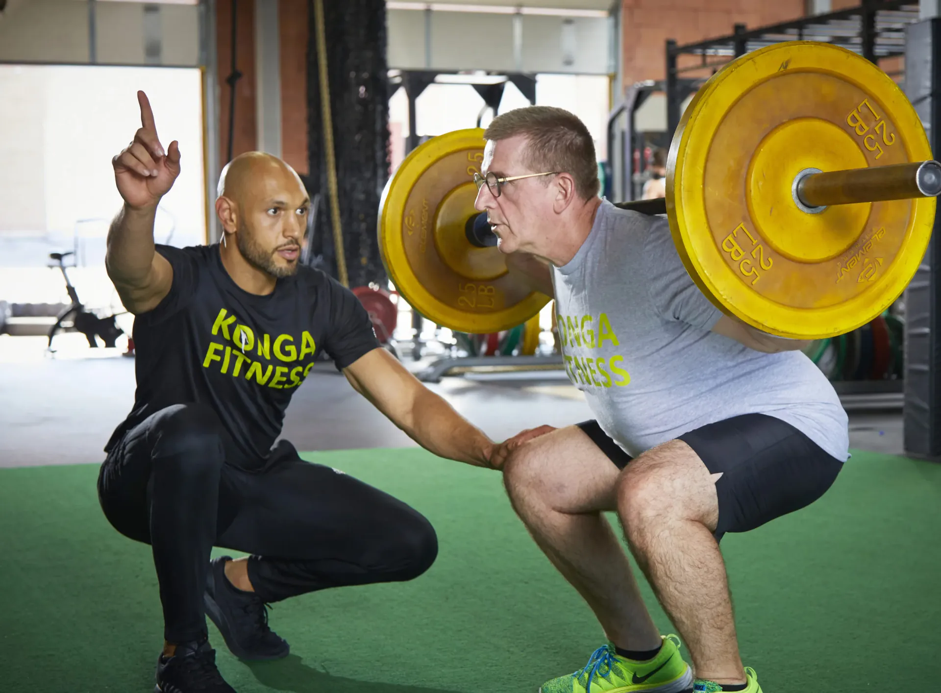 Khaled coaching a member through a barbell squat