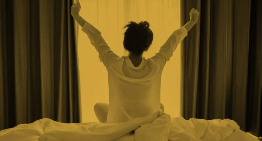 Person sitting up in bed and stretching both arms