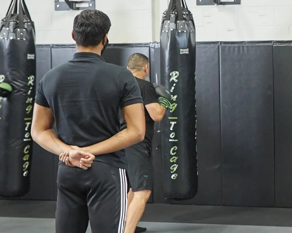 Coach observing members training on punching bags