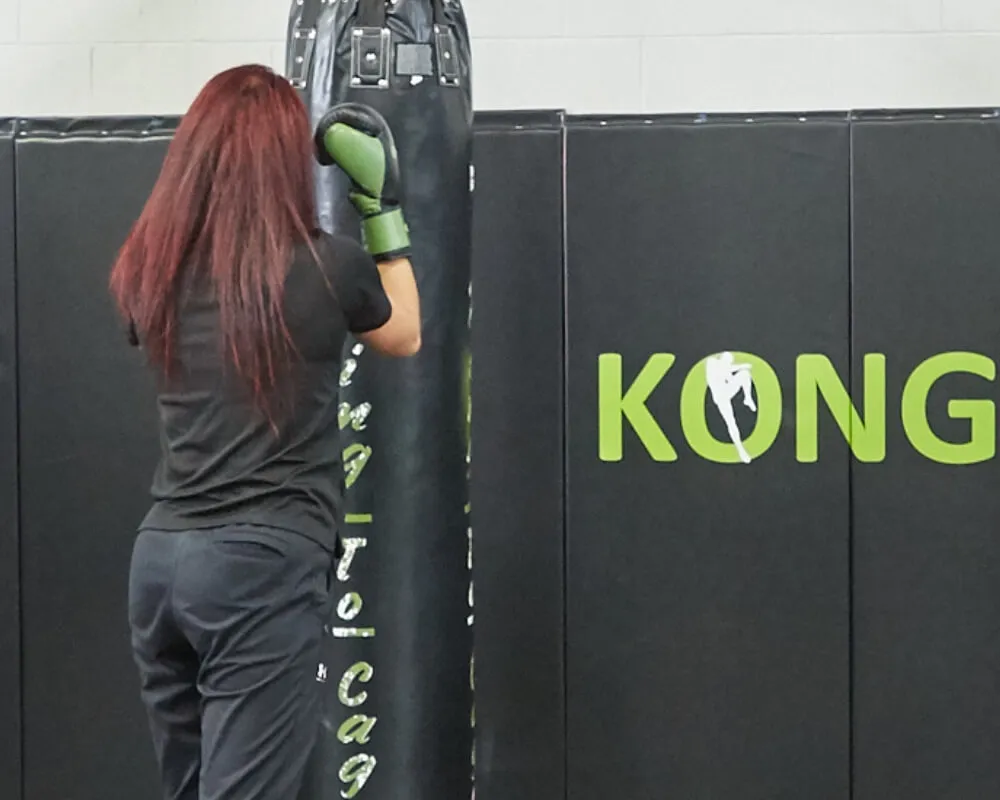 Woman wearing boxing gloves training on a heavy bag