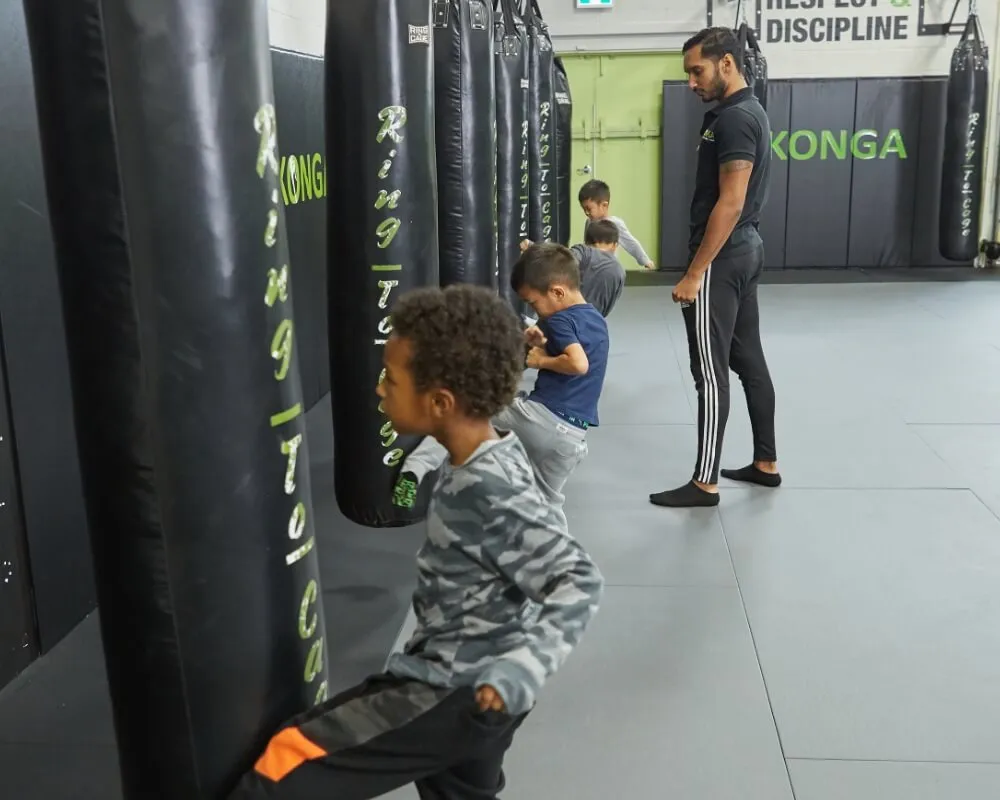 Children practising on punching bags with a coach