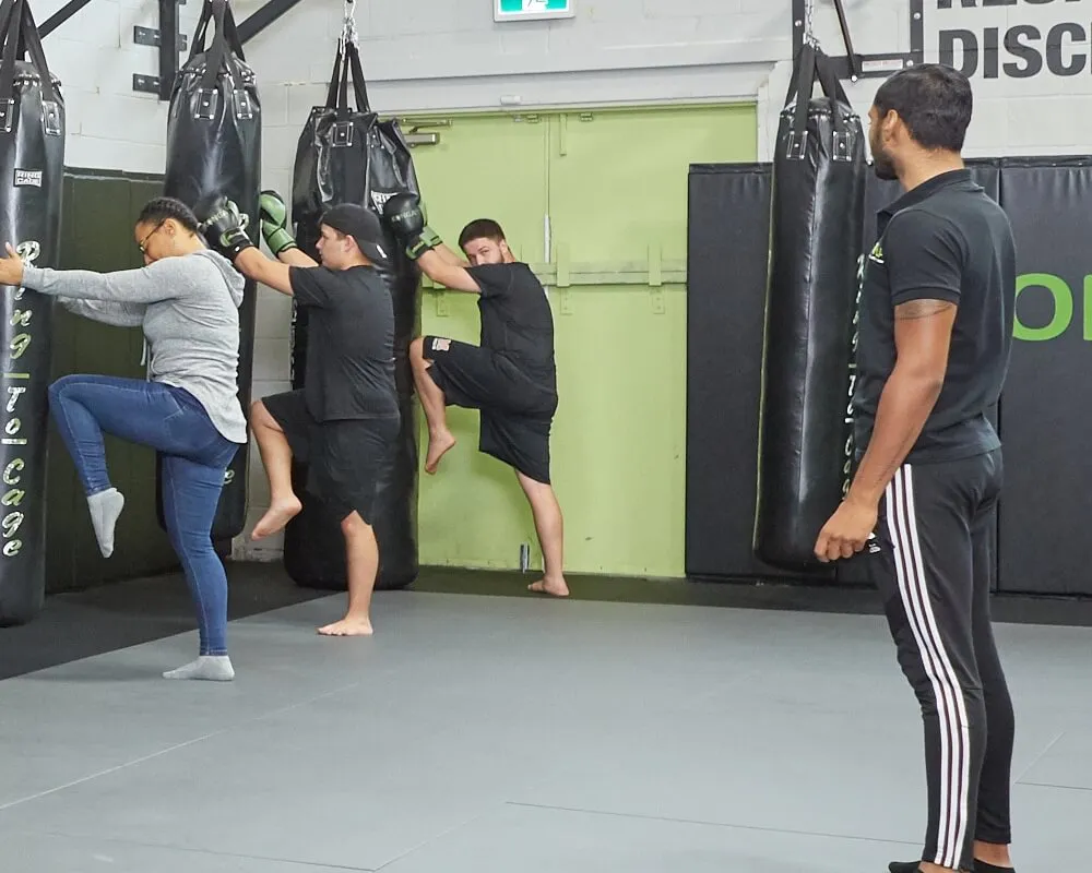 Coach supervising a Muay Thai class on the heavy bags