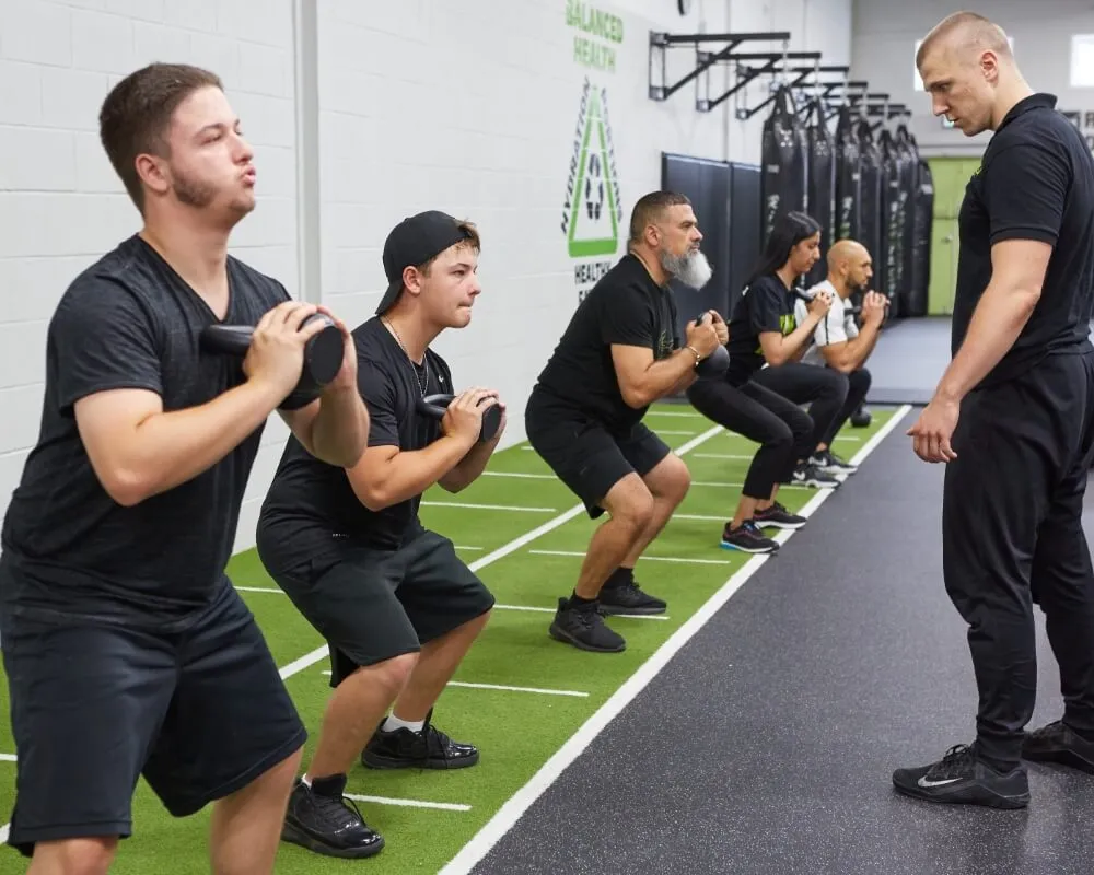Coach leading members through weighted squats