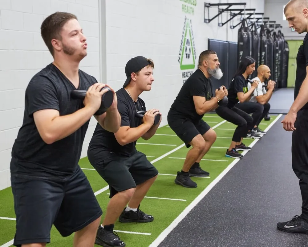 Members performing weighted squats in a group class
