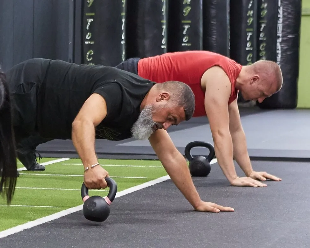 Members doing kettlebell rows from a plank position