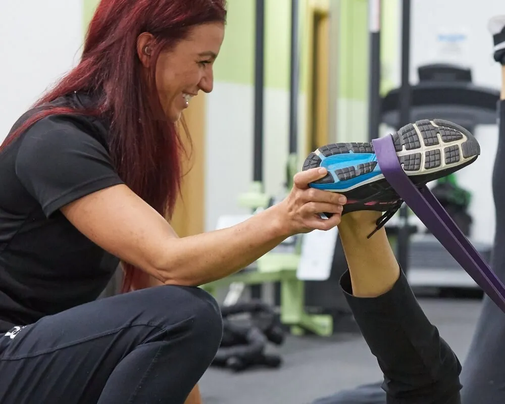 Trainer reviewing a phone while resting beside gym equipment