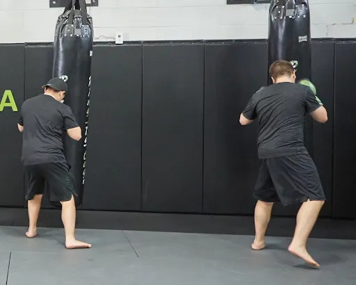 Two members practising punches on heavy bags