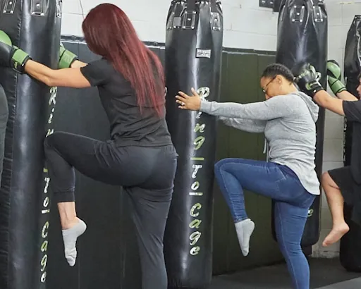 Women practising knee strikes against punching bags