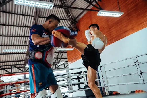 Martial arts student kicking a pad held by a training partner