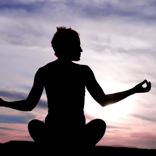 Silhouette of a person seated in meditation at dusk
