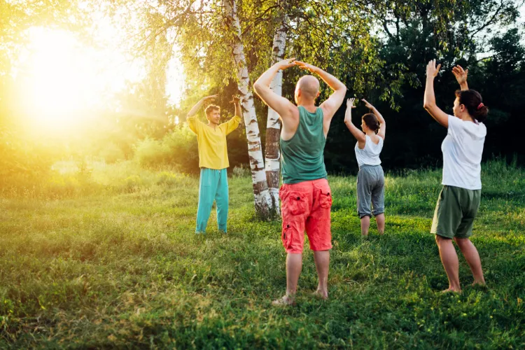 Group practising yoga stretches outdoors in sunlight