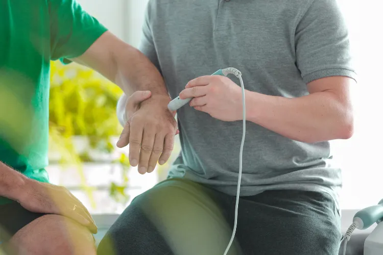 Practitioner applying a handheld treatment device to a client's wrist