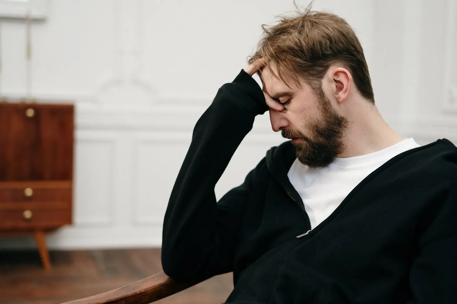 Man seated with a hand resting against his forehead