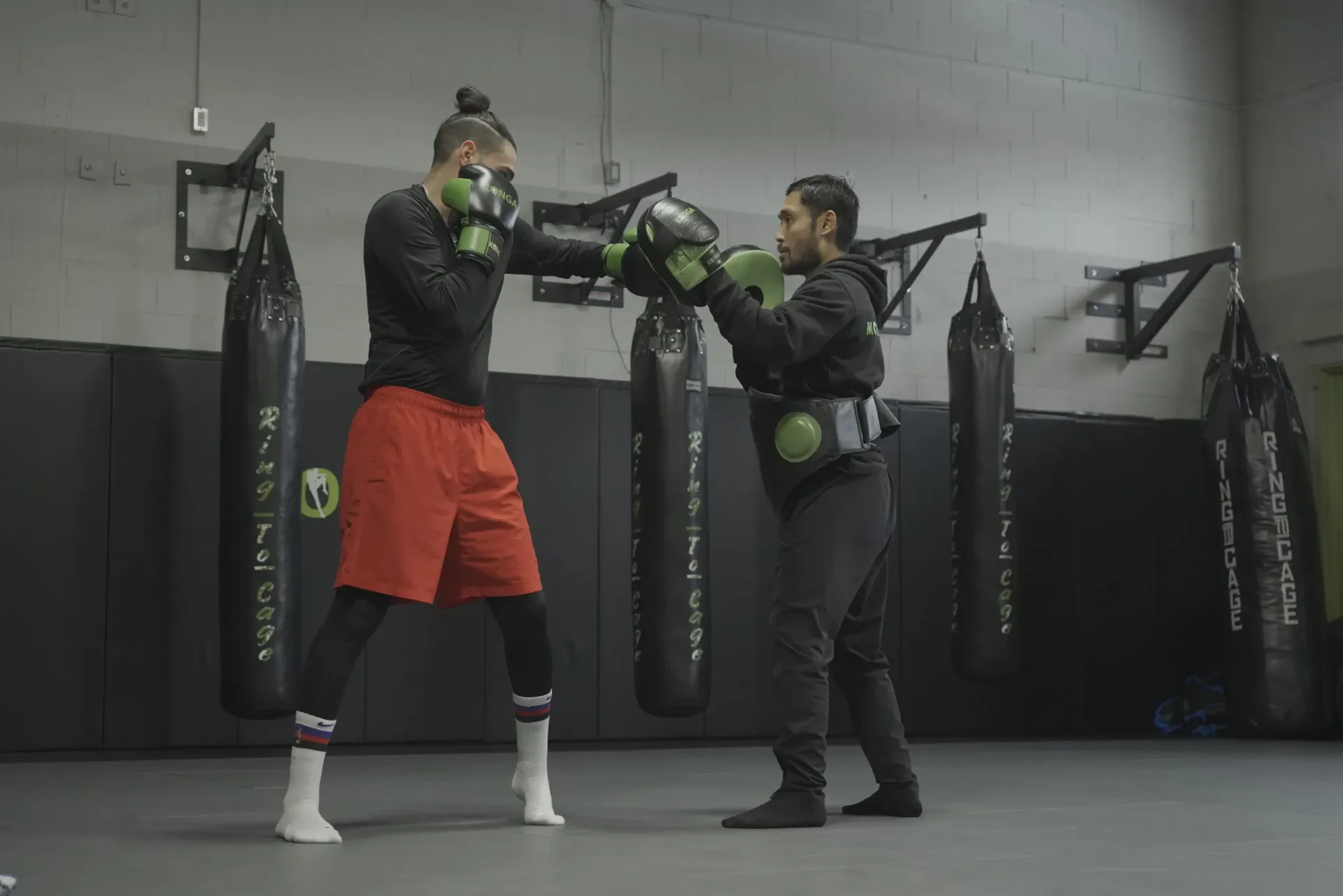 Two members practising boxing with gloves in the gym
