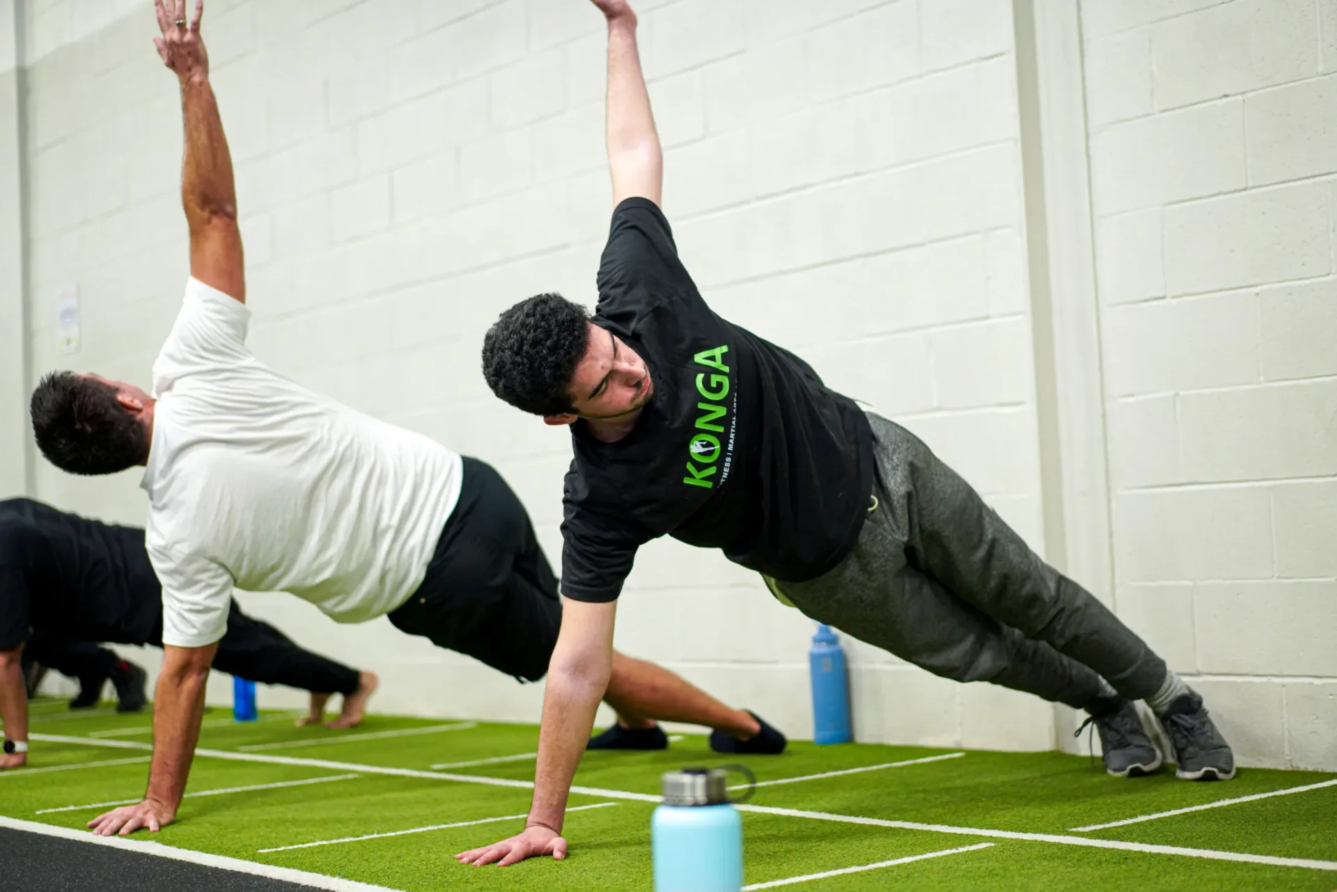 Members performing side planks with one arm raised