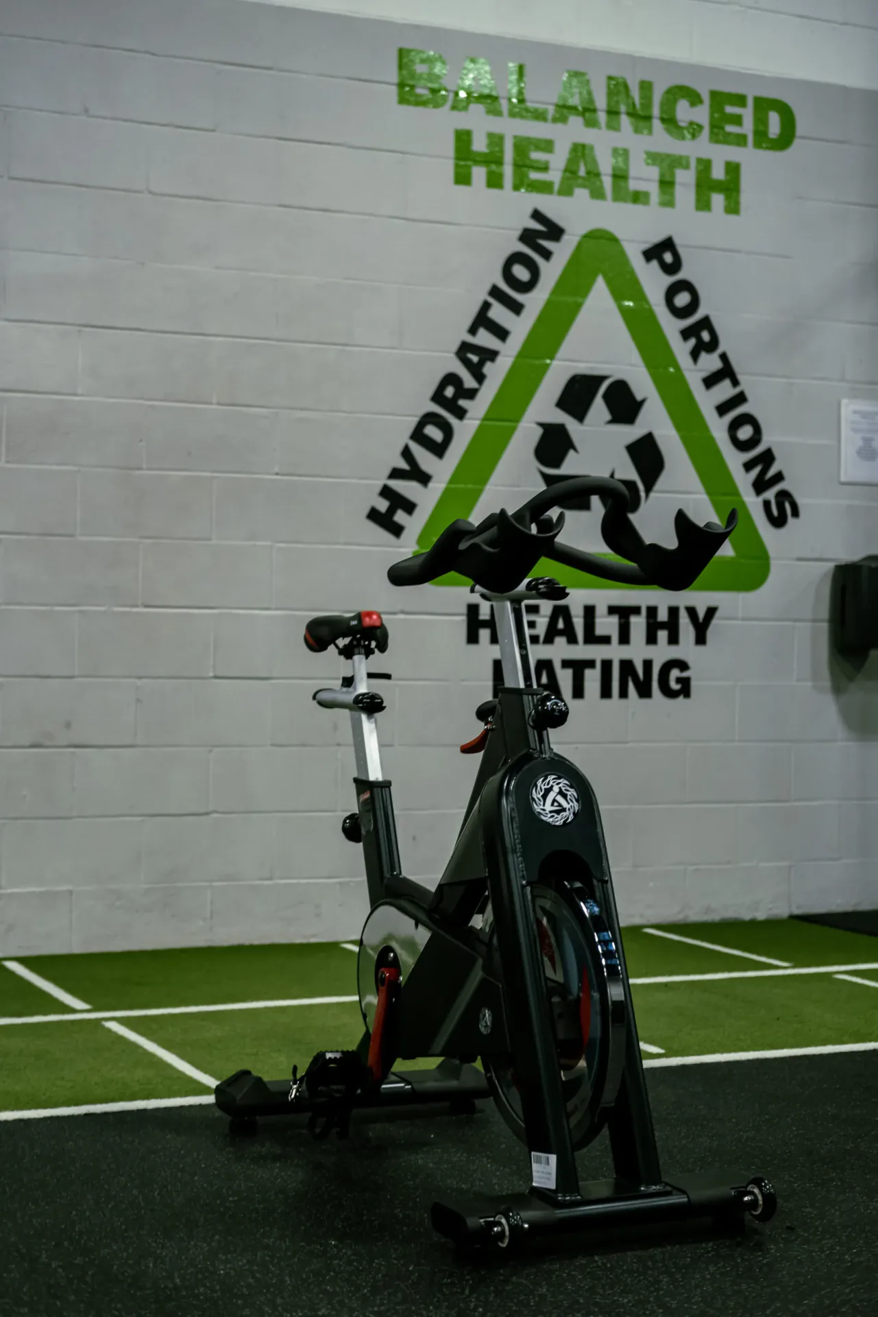 Stationary exercise bike beside the gym's Balanced Health mural