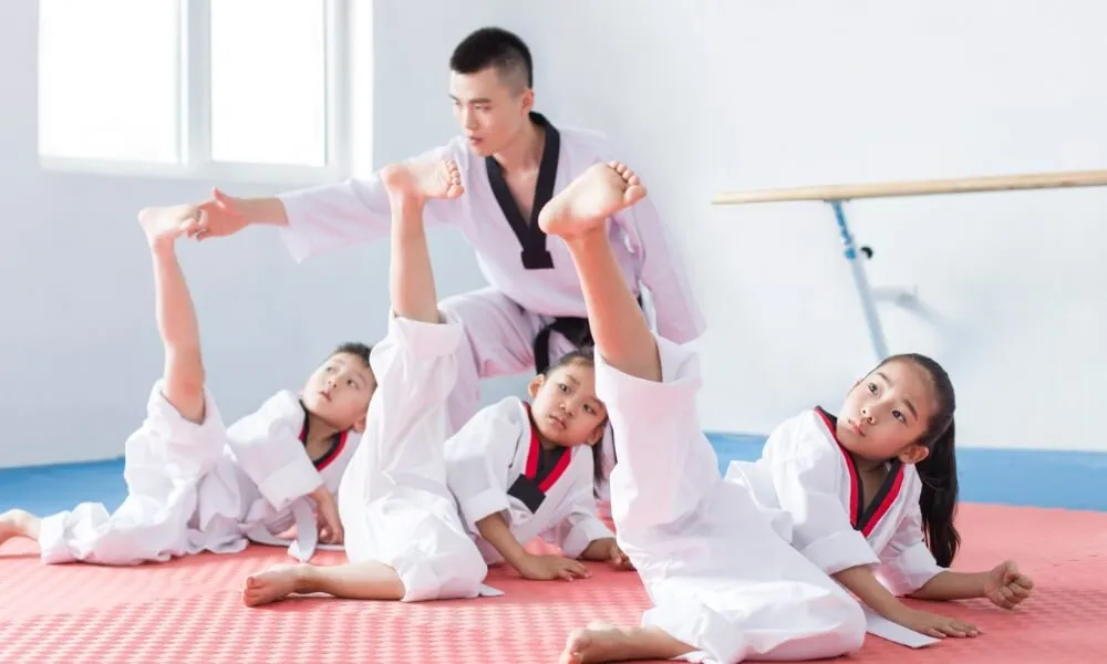 Instructor leading children through stretches in martial arts uniforms