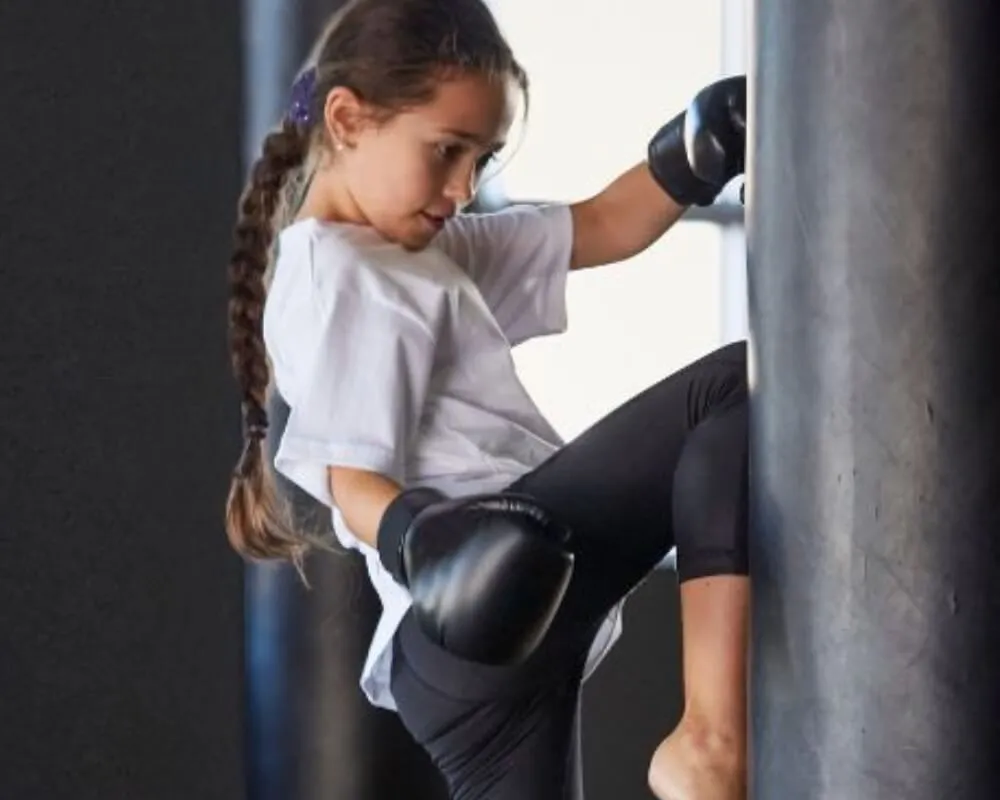 Child practising a knee strike against a punching bag
