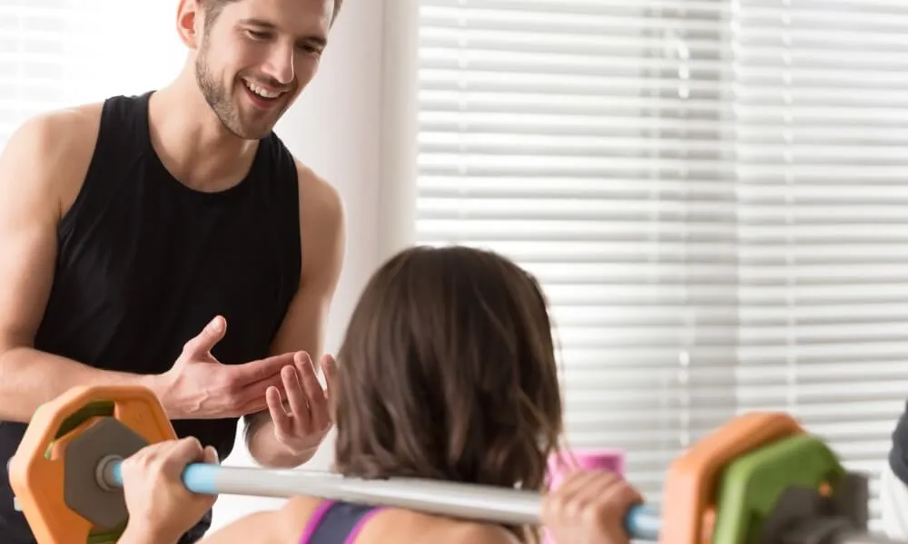 Personal trainer supervising a seated client's weighted exercise