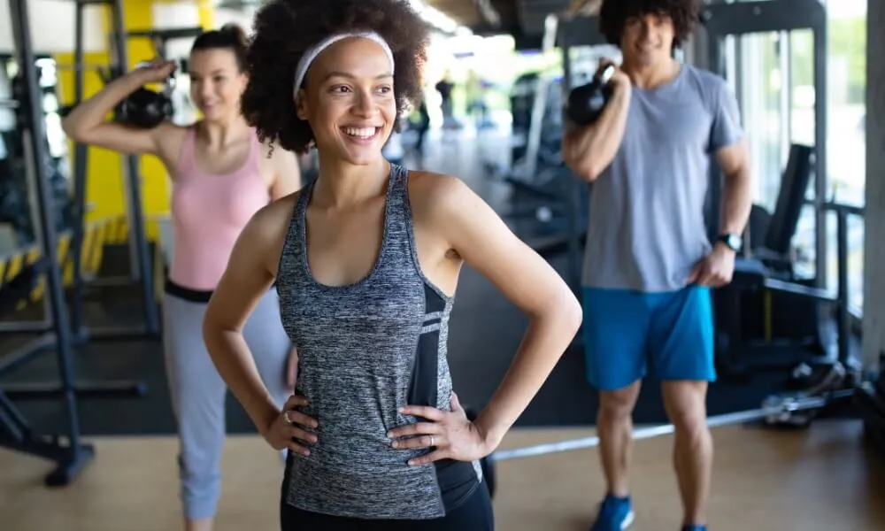 Personal trainer standing in a gym with members exercising behind her