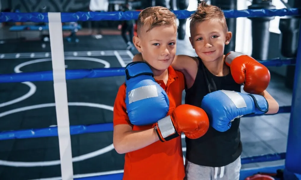 Two children wearing boxing gloves posing together in a ring