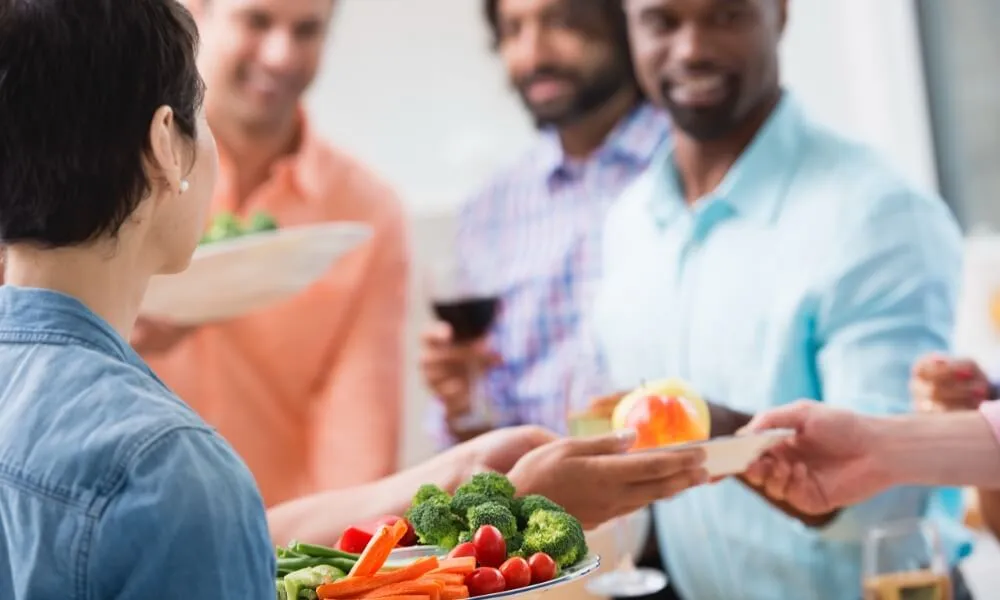 People sharing bowls of fresh vegetables at a table
