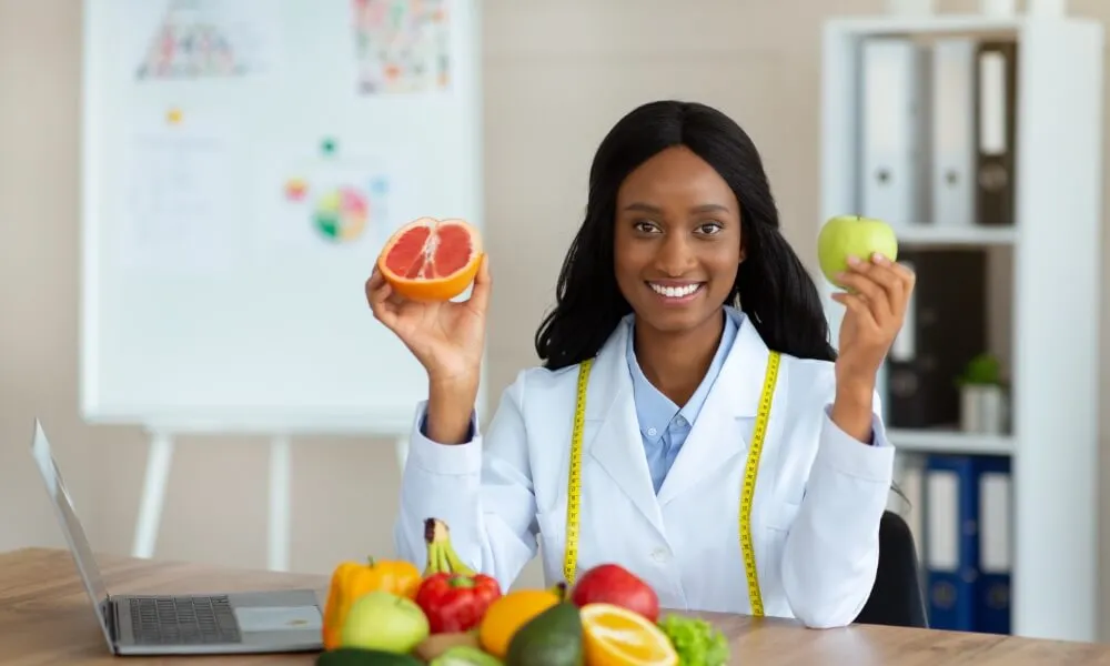 Nutrition professional holding fruit beside a plate of vegetables