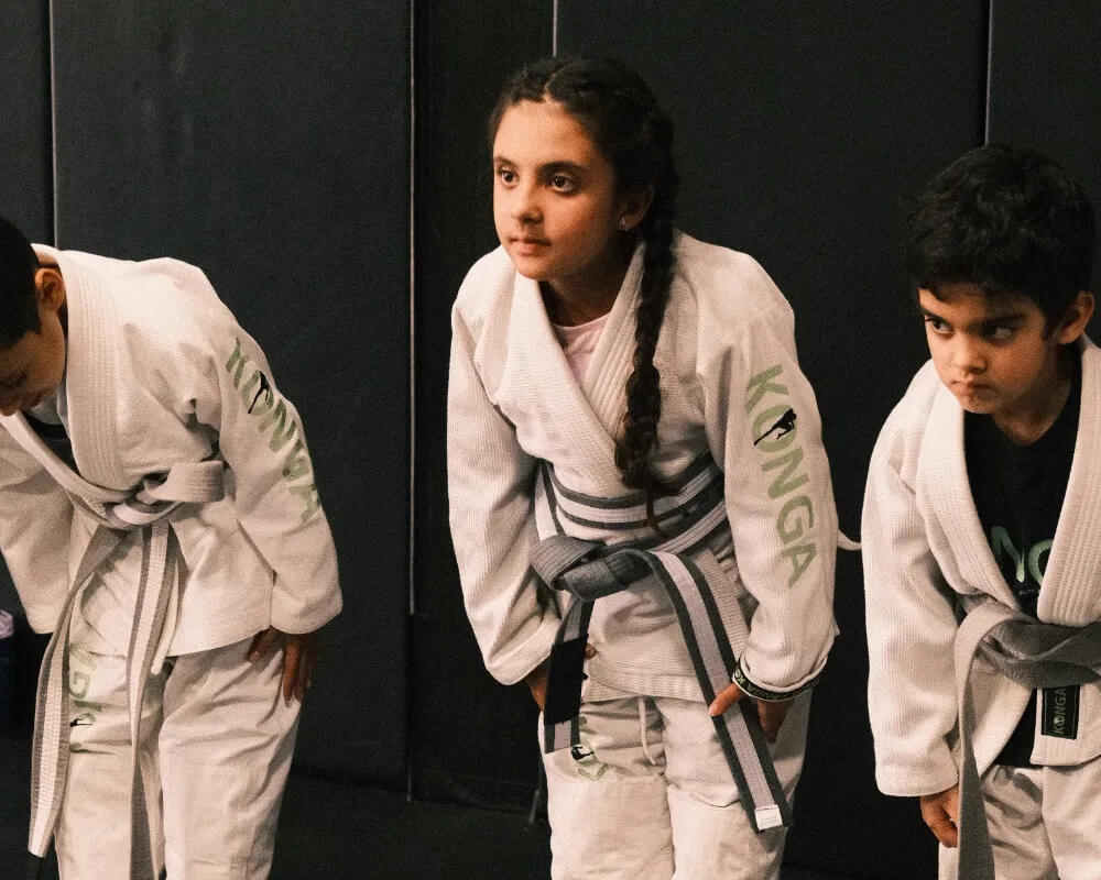 Children in martial arts uniforms listening during class