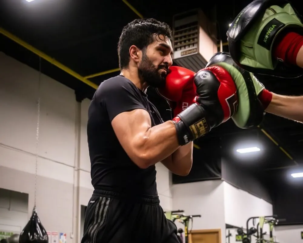 Boxer practising punches with red gloves and focus mitts