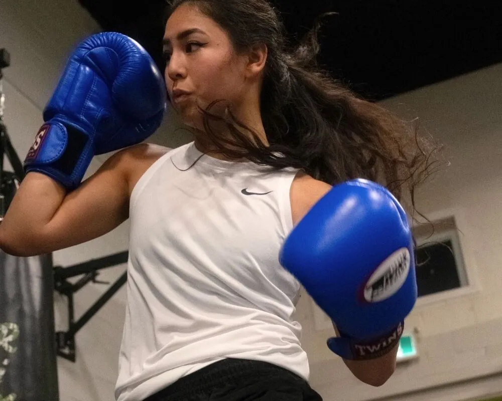 Woman practising punches with blue boxing gloves