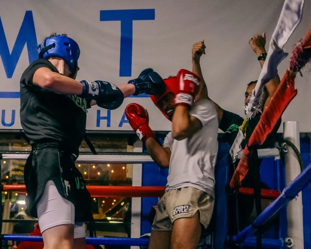 Two boxing partners practising punches with focus mitts in a ring